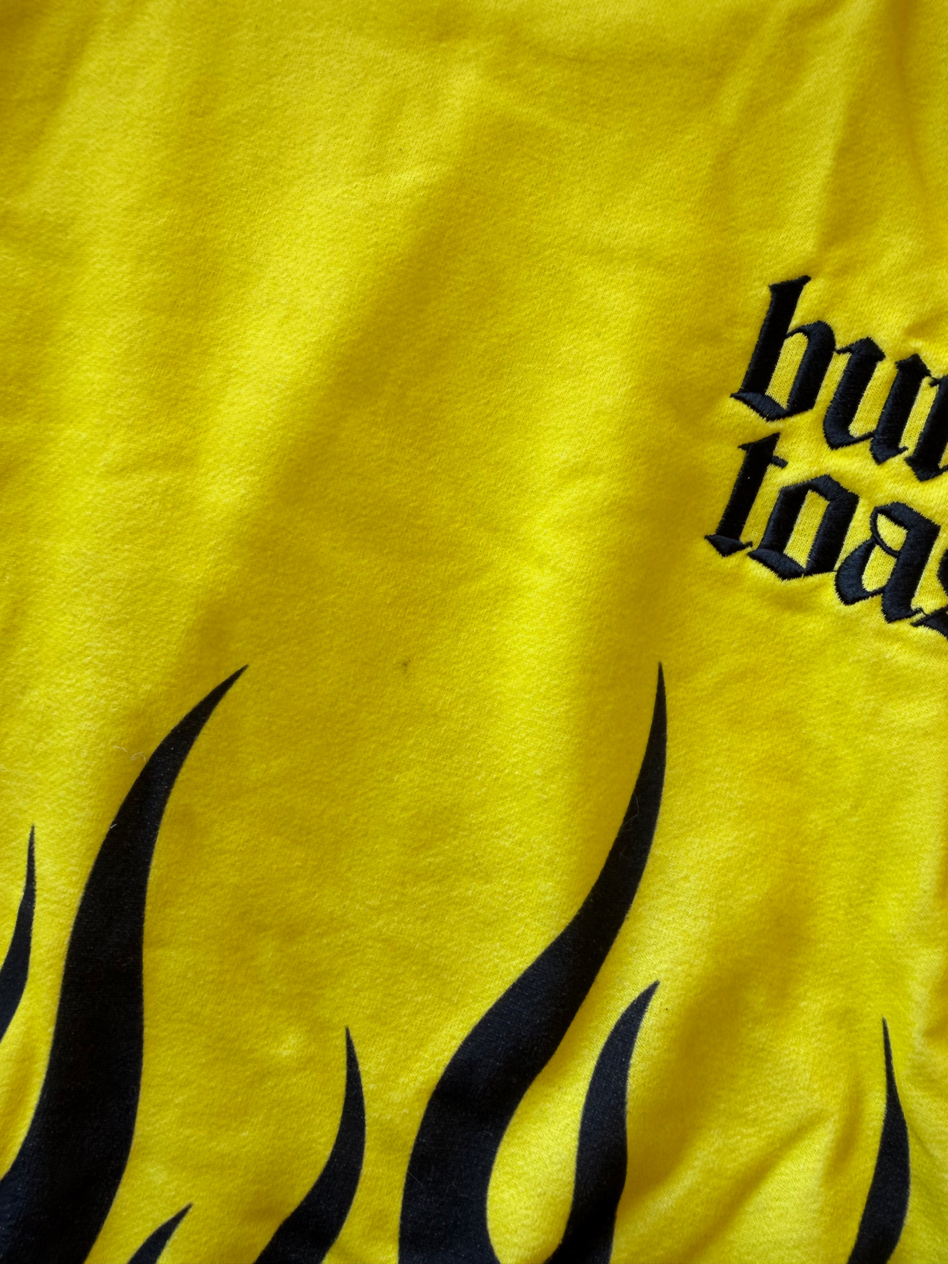 Close-up of a bright yellow fabric surface with black flame graphics and partial black gothic text reading 'burn toast'