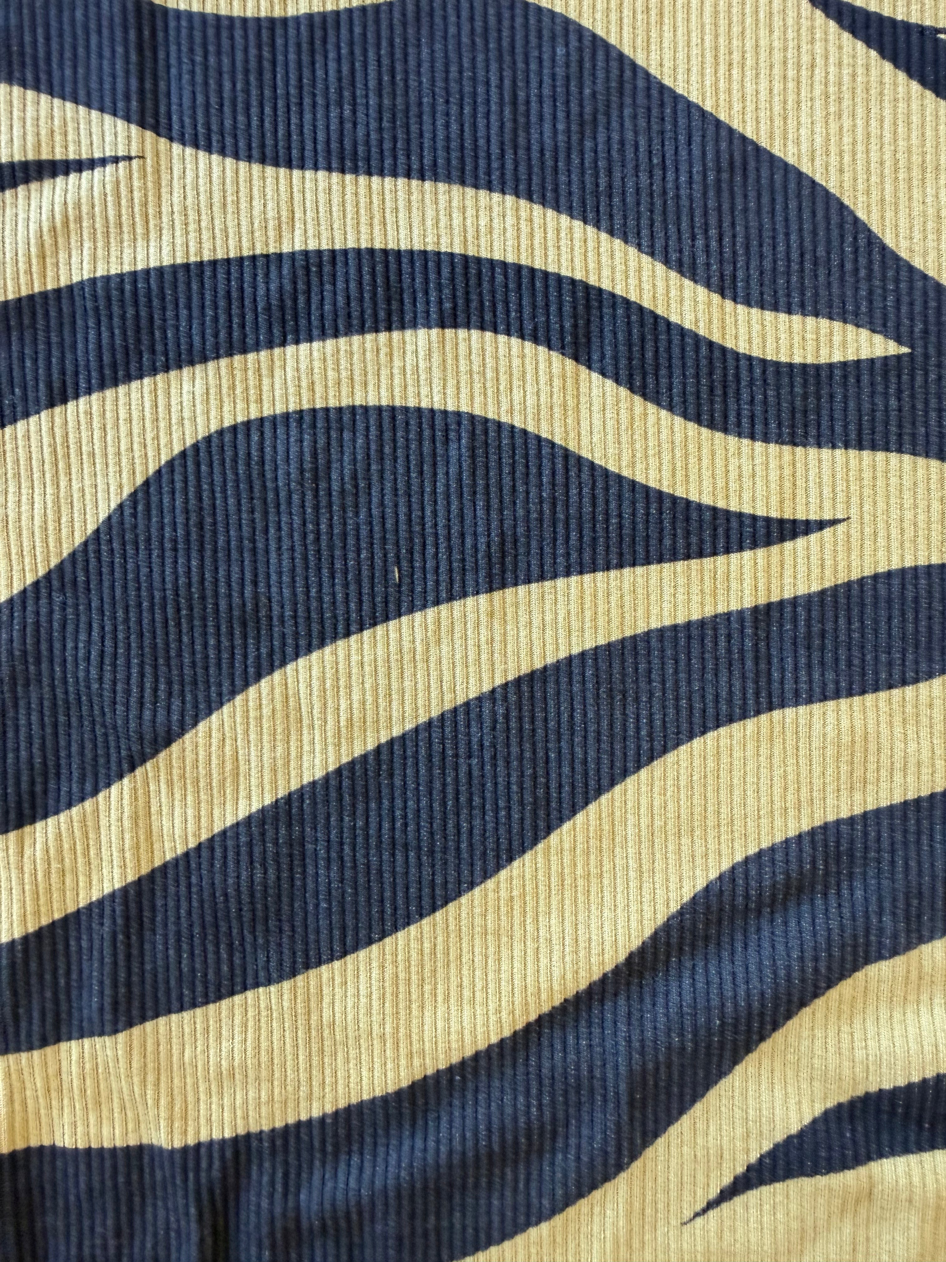 A close-up of a ribbed fabric with a bold wavy zebra-like pattern in green and black
