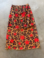 A leopard-print skirt with red star motifs, laid flat on a gray concrete floor
