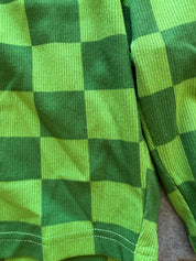 Close-up of a green and lime green checkered fabric garment, showing the ribbed texture and stitching