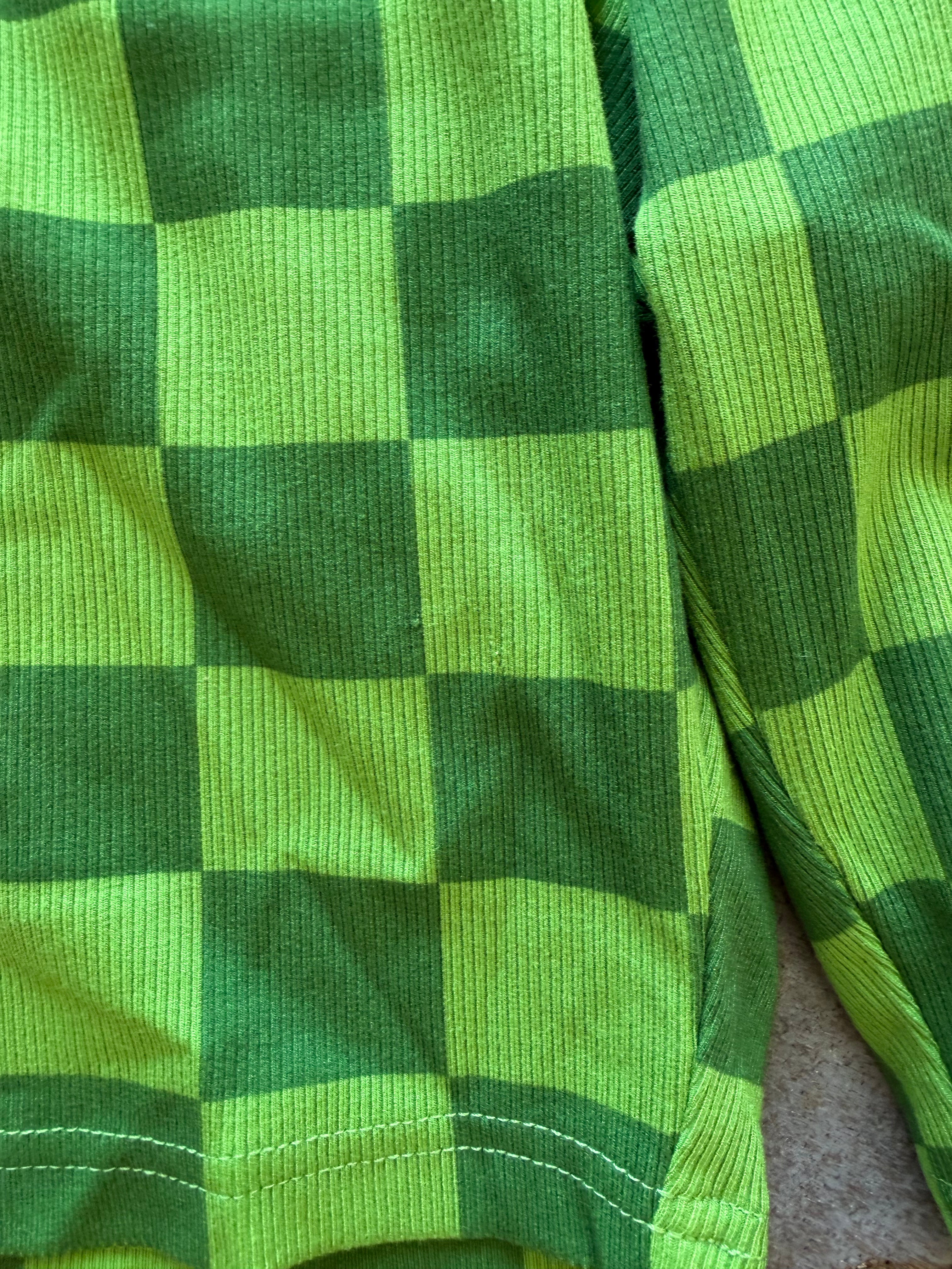 Close-up of a green and lime green checkered fabric garment, showing the ribbed texture and stitching