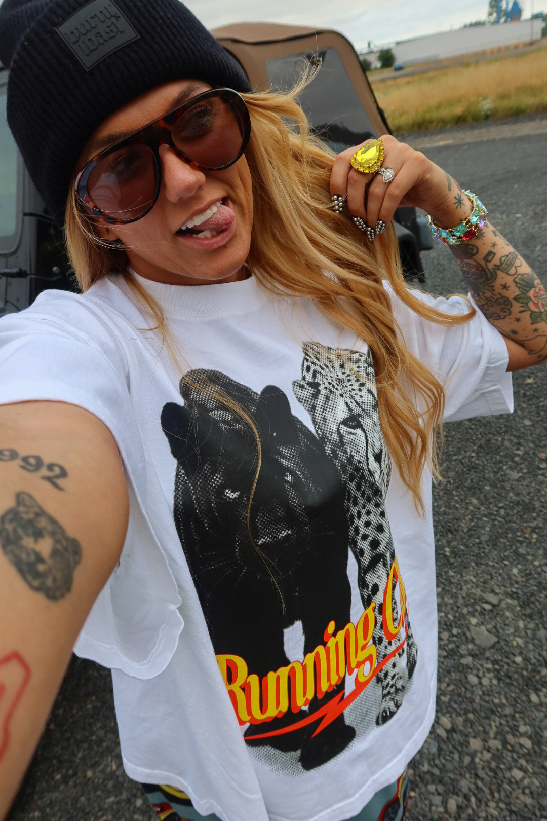 A woman taking a selfie outdoors wearing a white graphic t-shirt with a black bear and leopard print and the words 'Running Club'