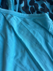 Close-up of a light blue fabric garment, showing the texture of the material and a portion of a darker blue and black patterned fabric in the background
