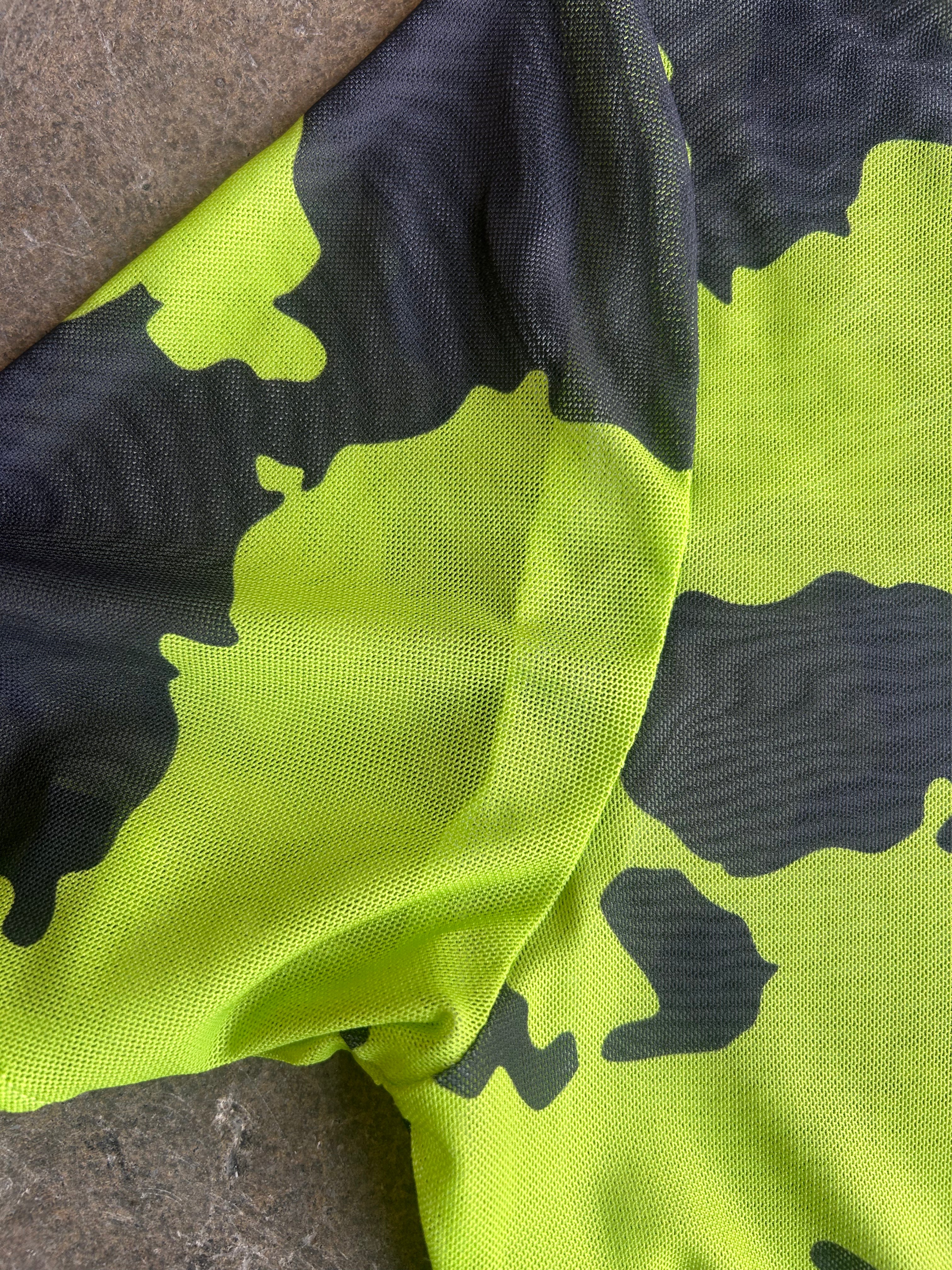 Close-up of a neon yellow-green and black camouflage patterned fabric, showing the textured woven material and folds