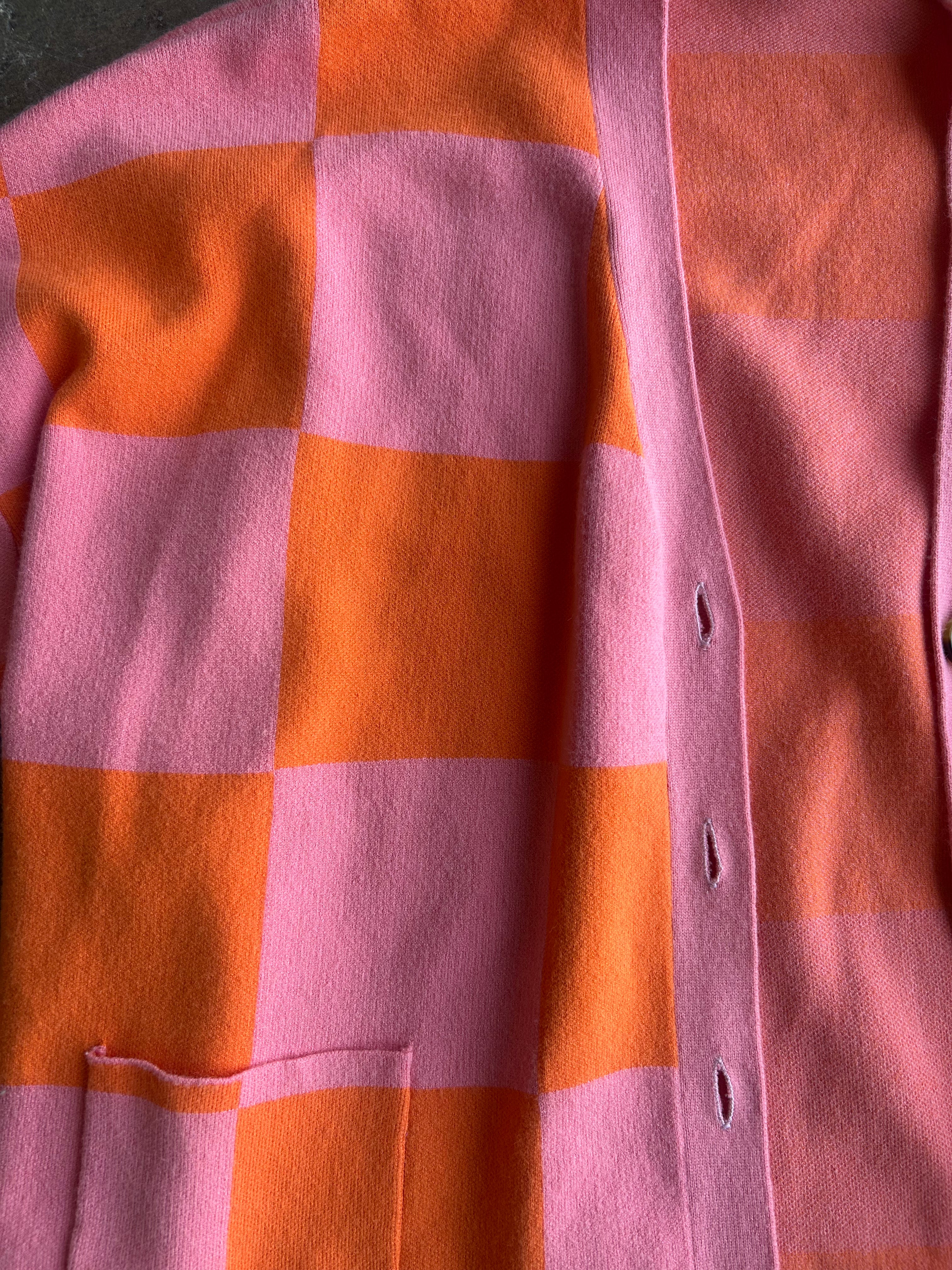 Close up of a pink and orange checkered cardigan, flat lay frontal view