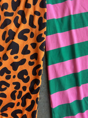 Close-up of two ribbed fabric panels side by side: one orange with black leopard spots and one with alternating green and pink horizontal stripes