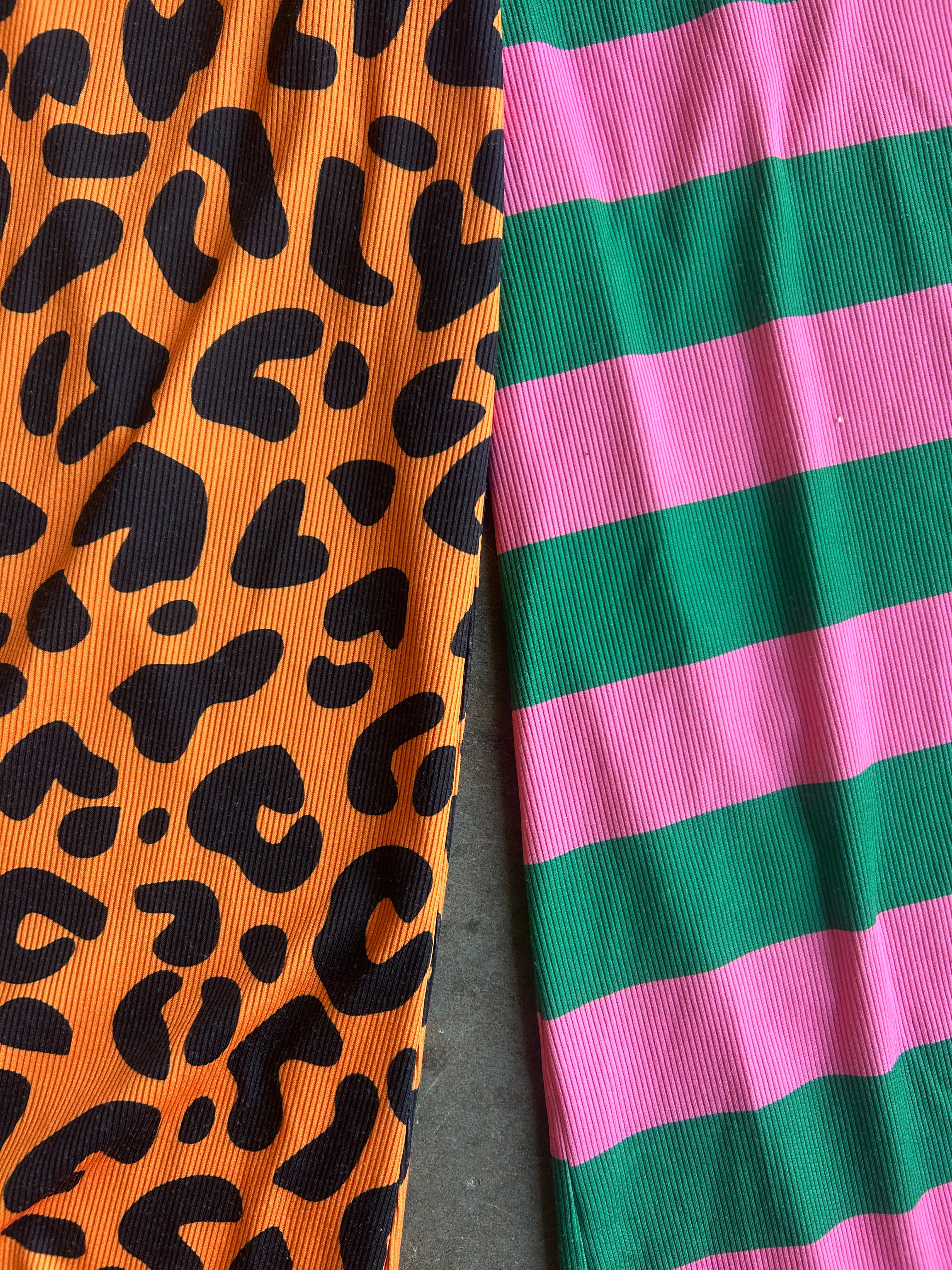 Close-up of two ribbed fabric panels side by side: one orange with black leopard spots and one with alternating green and pink horizontal stripes