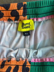 Close-up of a pair of ribbed shorts with a bright yellow Burnt Toast brand label and a multicolor patterned design in orange, green, black, pink, and white
