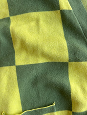 Close-up of a yellow and dark green checkered fabric with a small pocket visible at the bottom