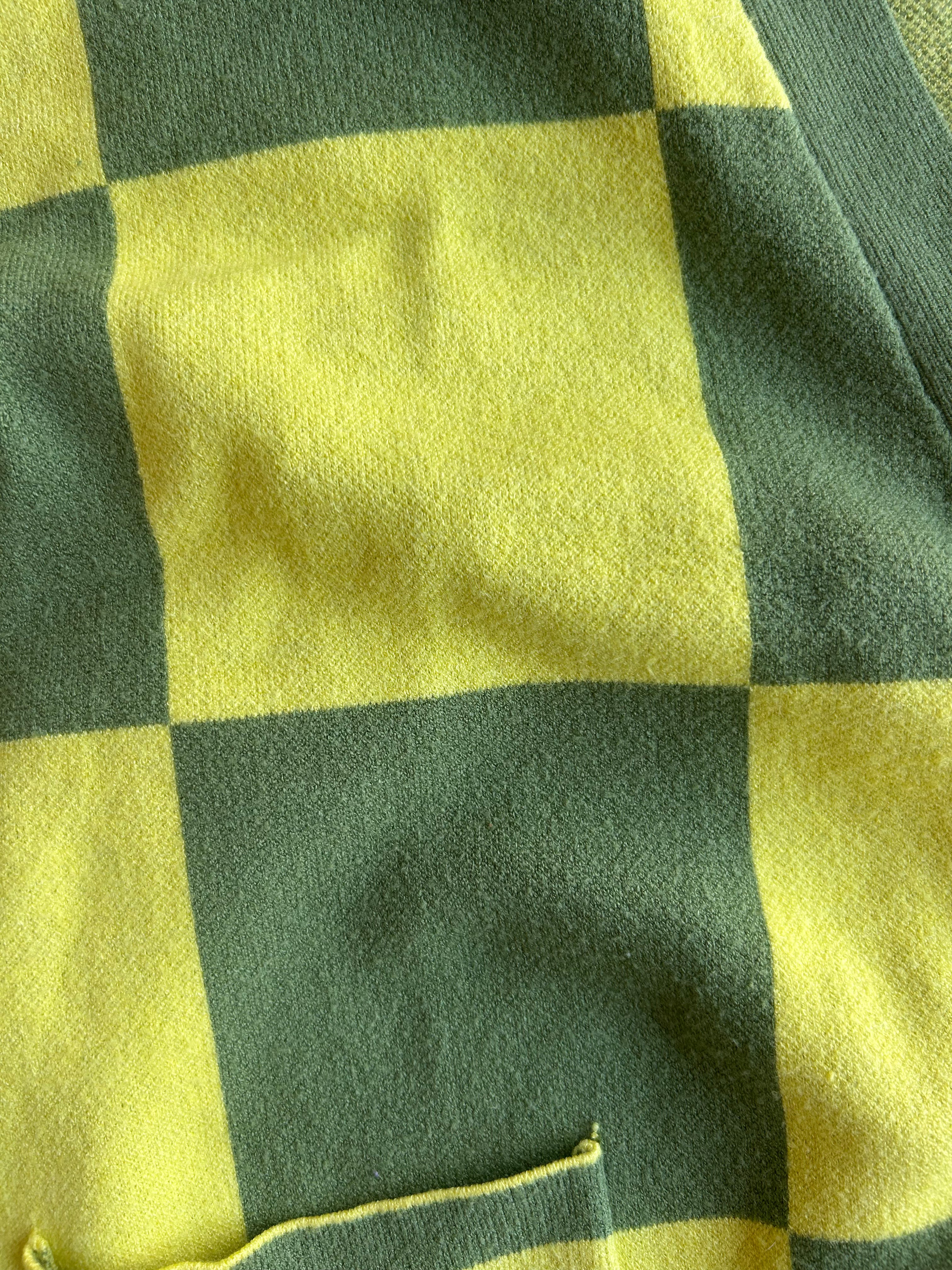 Close-up of a yellow and dark green checkered fabric with a small pocket visible at the bottom