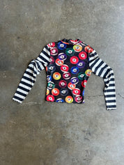 A long-sleeve shirt laid flat on a concrete floor, featuring a black body with a colorful pool ball pattern on the chest and black-and-white striped sleeves, back view