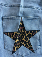 Close-up of the back pocket of a light blue denim jacket, featuring a large star patch with a leopard print pattern in black, brown, and tan