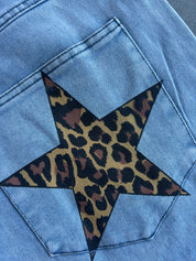 Close-up of a light blue denim jacket showing a large star-shaped leopard print patch applied to the back pocket