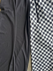 Close-up of two fabric panels laid side by side: one solid dark charcoal ribbed material and one black-and-white checkerboard patterned material