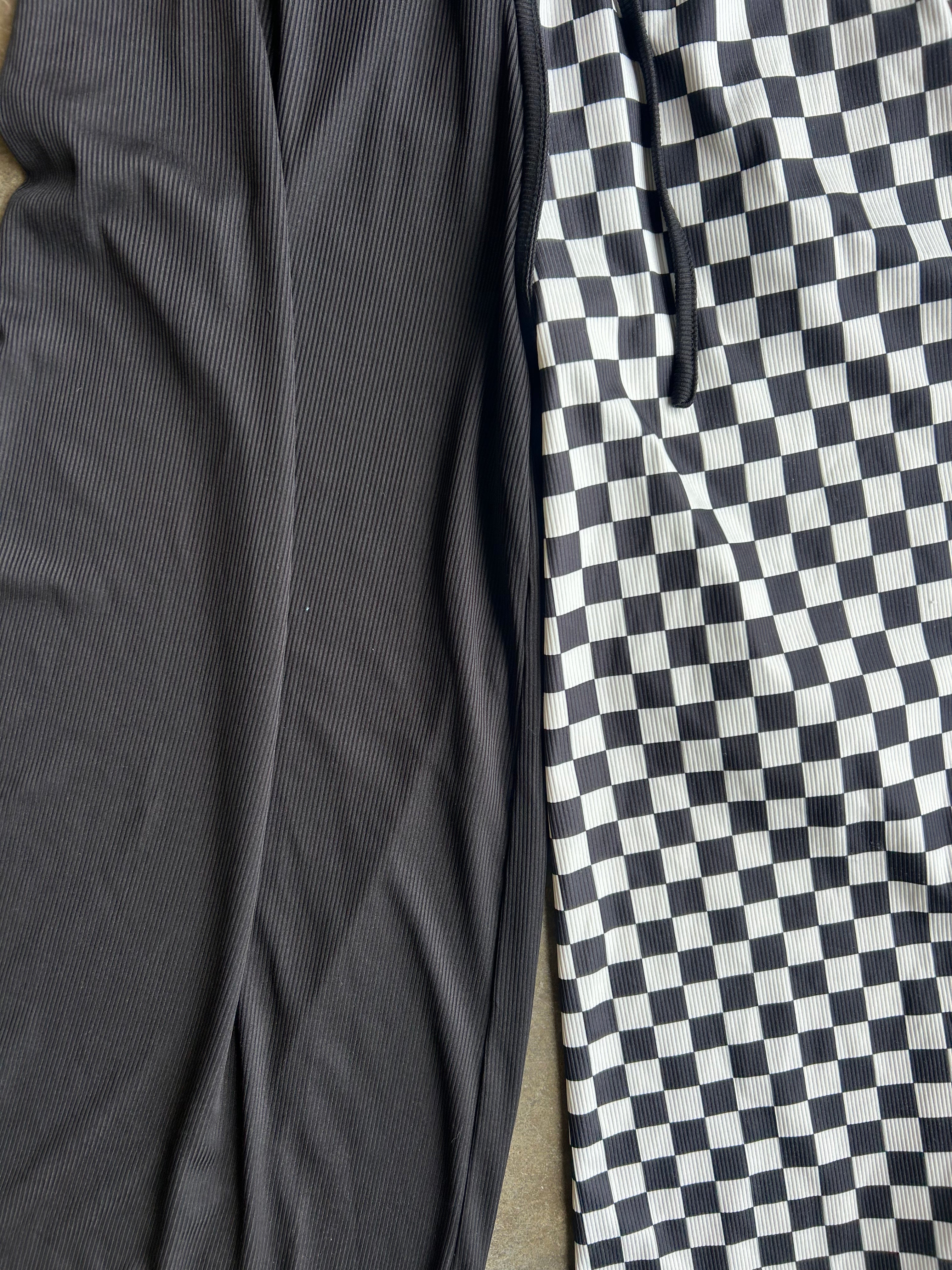 Close-up of two fabric panels laid side by side: one solid dark charcoal ribbed material and one black-and-white checkerboard patterned material