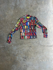 A long-sleeve crewneck shirt with a dense, colorful print of classic cars in red, blue, yellow, and black, laid flat on a textured gray concrete floor
