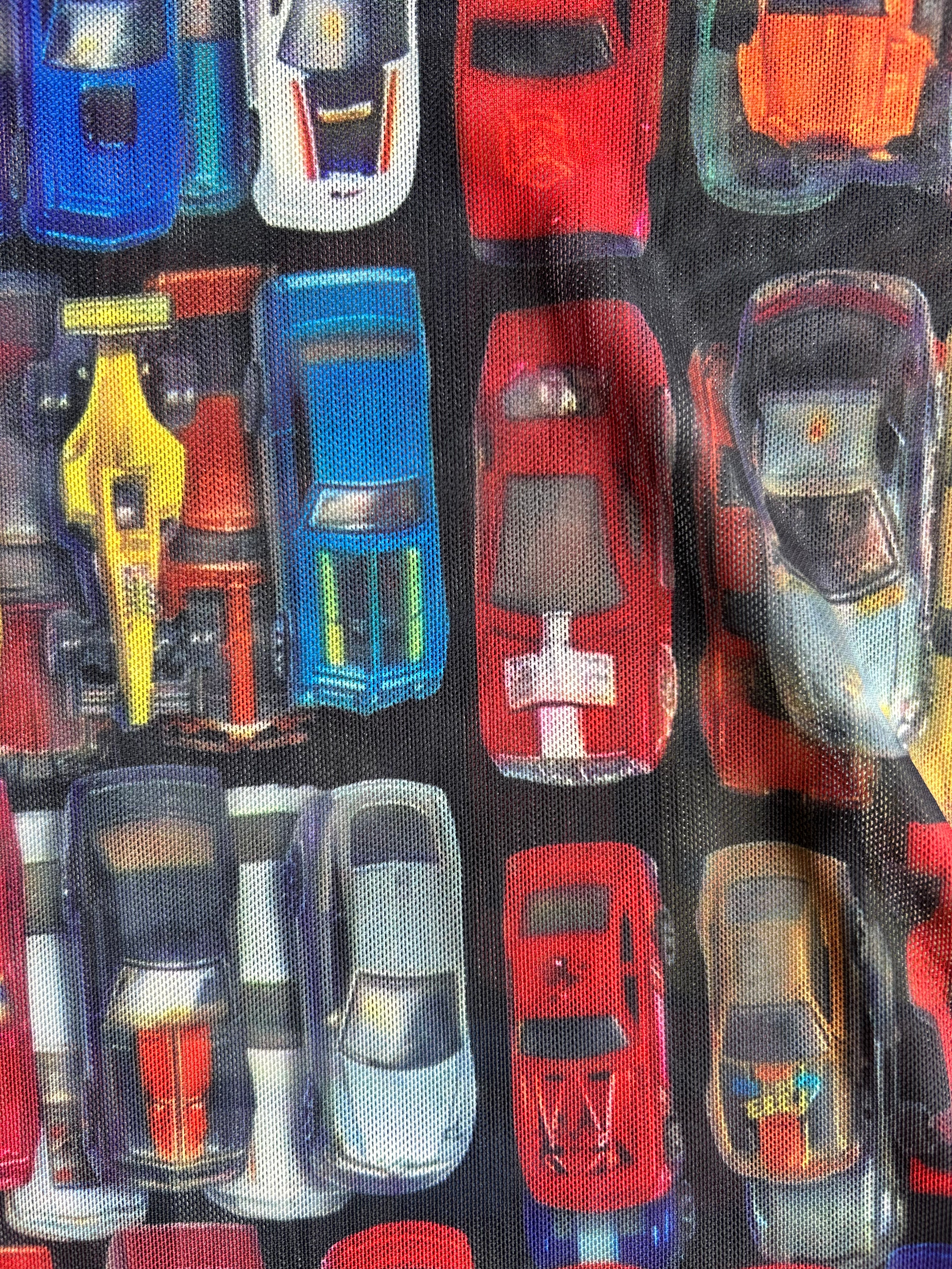 Close-up of a fabric or material print featuring a repeating pattern of colorful toy cars on a dark background