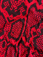 A close-up of a red and black snakeskin patterned fabric with a textured, ribbed surface