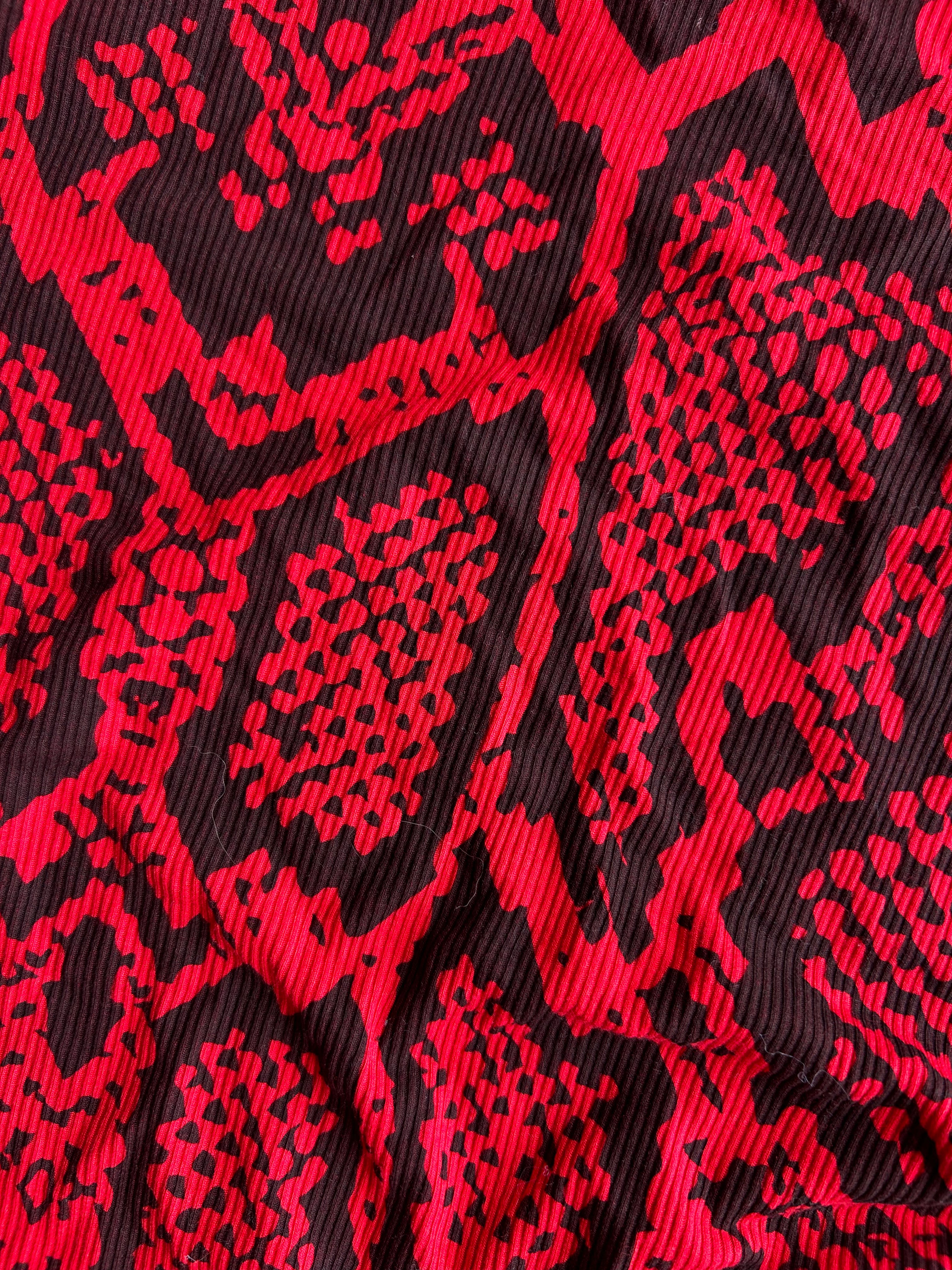 A close-up of a red and black snakeskin patterned fabric with a textured, ribbed surface