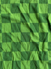 A close-up of a green and dark green checkered fabric with a ribbed texture, showing the pattern and material details