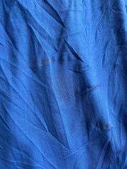 A close-up of crumpled blue fabric, likely cotton or linen, showing its textured weave and soft shadows in the folds