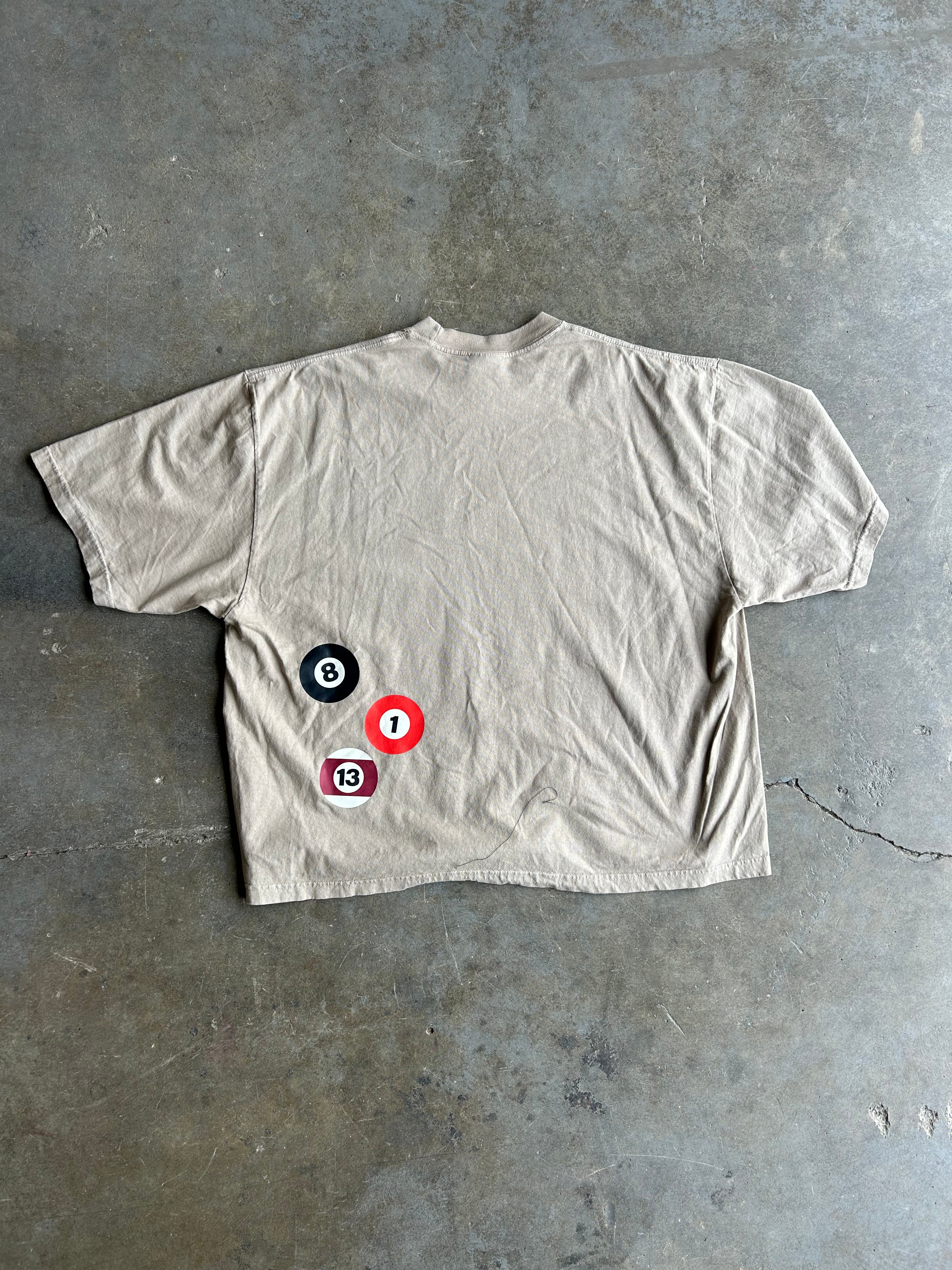 Back of beige tshirt with billiard balls, flat lay on a concrete floor