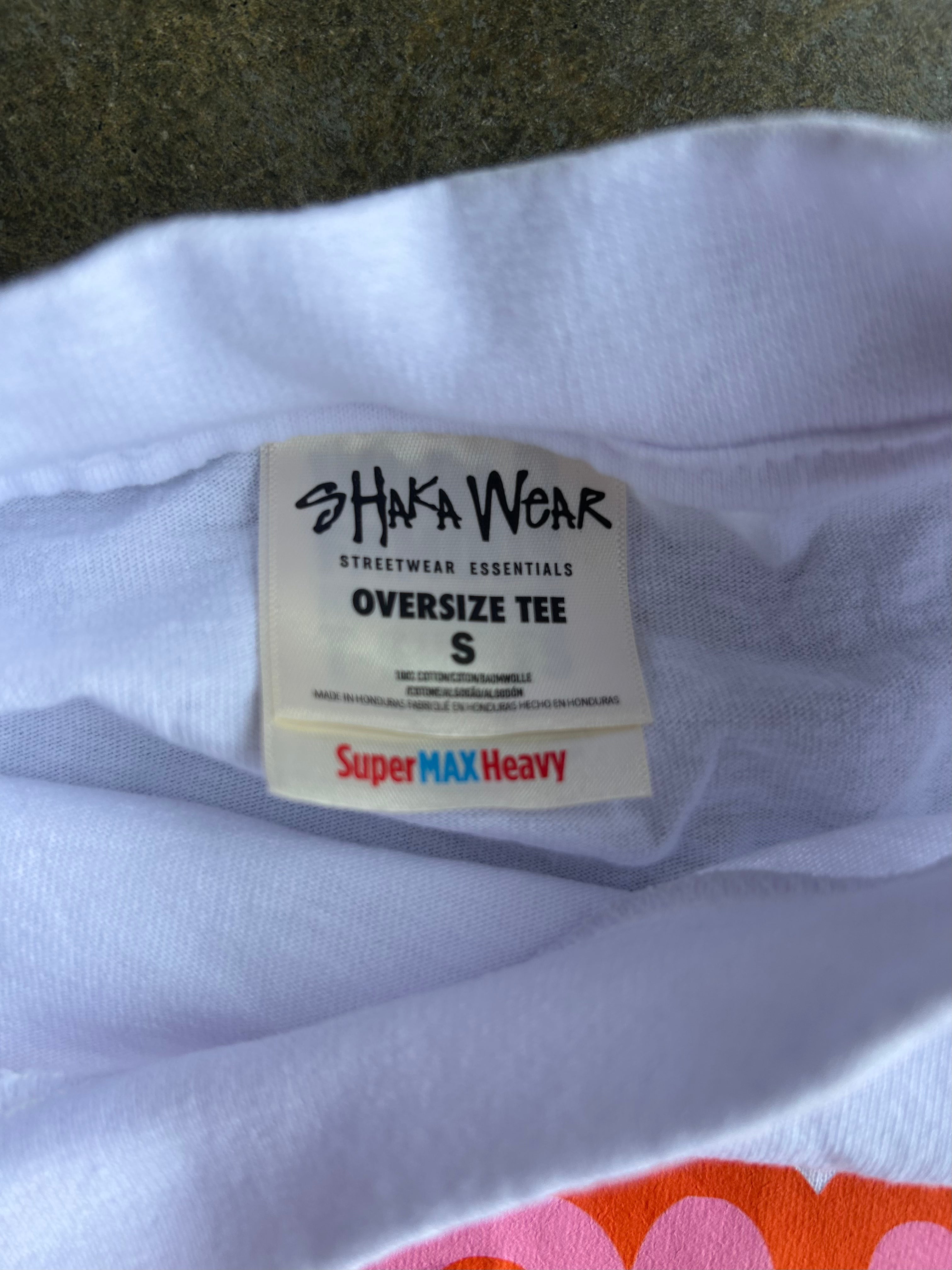 Close-up of the inside collar of a white oversized T-shirt showing the Shaka Wear brand label and 'Super MAX Heavy' text