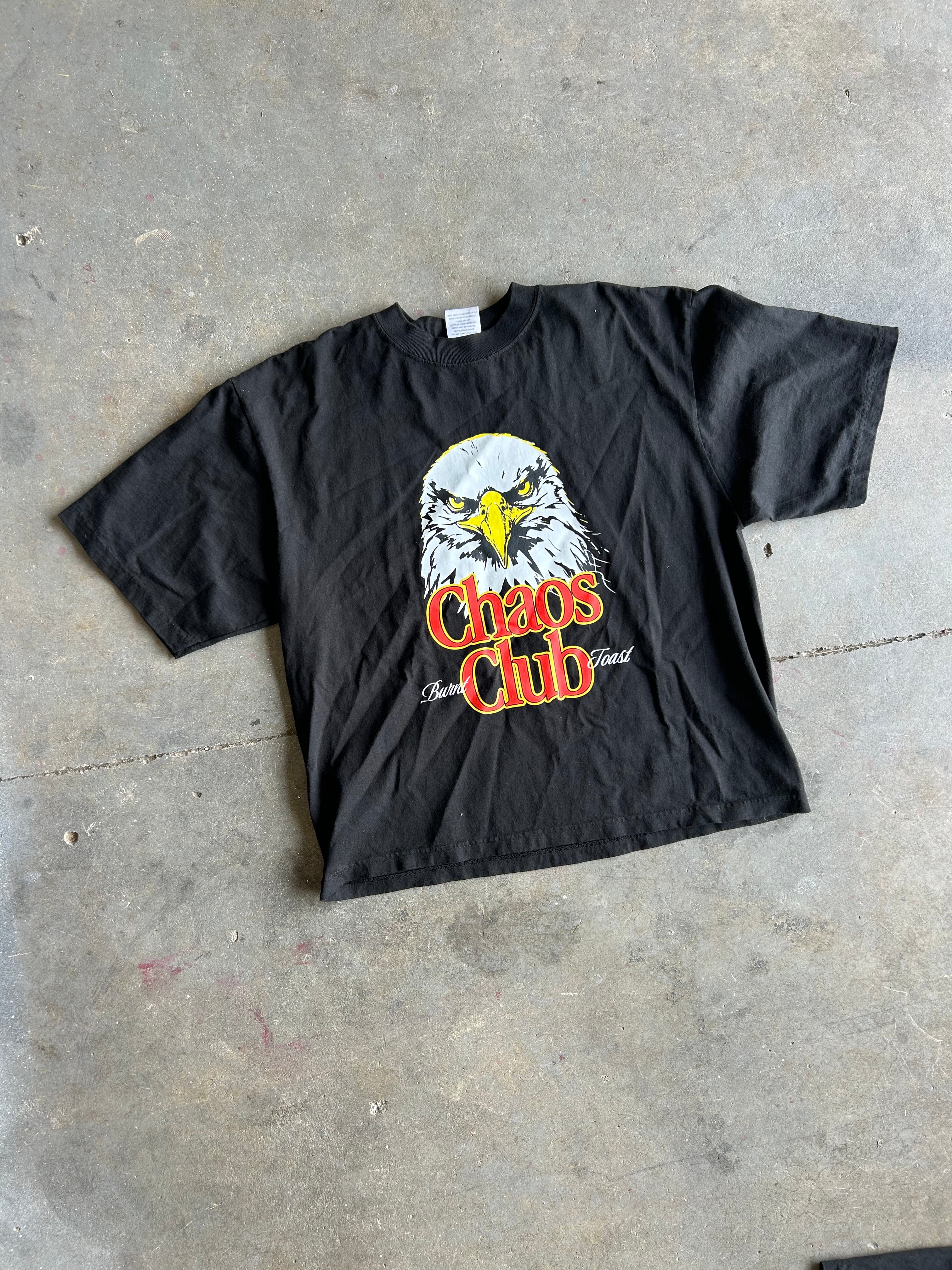 Black tee with eagle graphic and Chaos Club text on a concrete surface