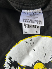 Close-up of a black heavy-weight t-shirt with a white and yellow graphic print, showing the inner neck label for Shiva Wear.