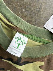 Close-up of a camouflage crewneck shirt showing the green ribbed collar, a white sewn-in label for Cotton Collective, and a size tag marked Small.