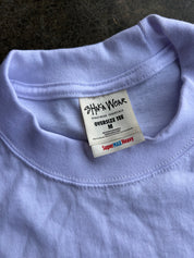 Close-up of a light lavender oversized t-shirt collar showing the inner brand label for 'Shaka Wear'.