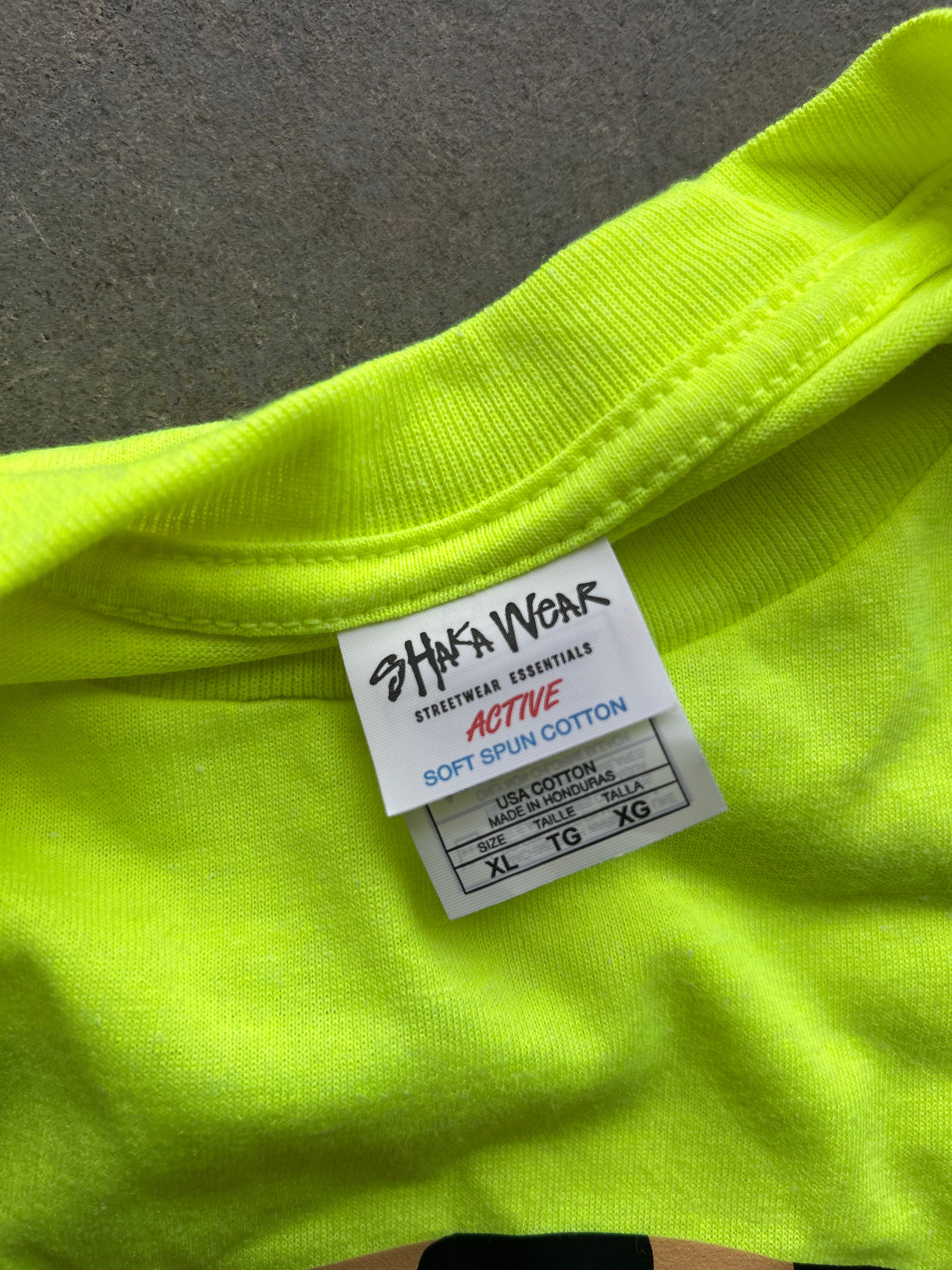 Close-up of a neon yellow-green t-shirt showing the inner neck label which reads 'SHA'S WEAR ACTIVE' and 'SOFT SPUN COTTON'.