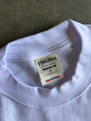 Close-up of a light lavender-purple crewneck t-shirt collar, showing a white inner neck label that reads 'SHAKA WEAR' and 'SUPER MAX HEAVY'.