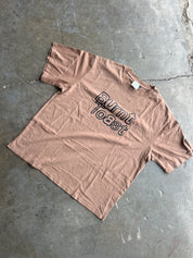 A dusty rose short-sleeve t-shirt with 'Burnt Toast' printed in black outline text across the chest, laid flat on a gray concrete floor.
