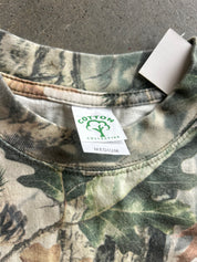 Close-up of a camouflage crewneck sweatshirt showing the inner collar label which reads 'COTTON COLLECTIVE' and 'MEDIUM', with a white retail tag attached.