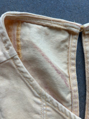 Close-up of a cream-colored garment with visible pinkish-red stained areas on the inner fabric, showing the texture of the textile and stitching