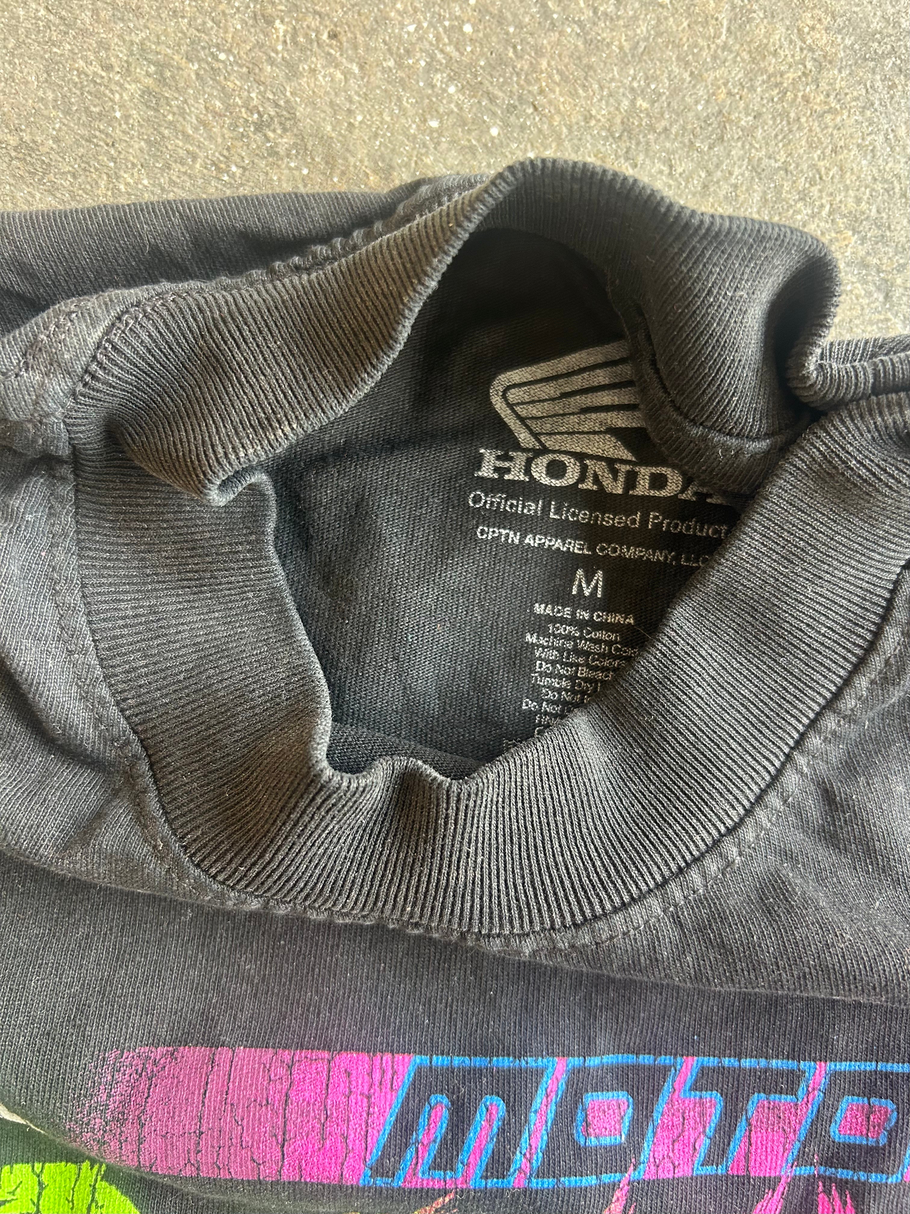 Close-up of a dark gray Honda crewneck t-shirt showing the inner neck label and part of a colorful graphic print at the bottom
