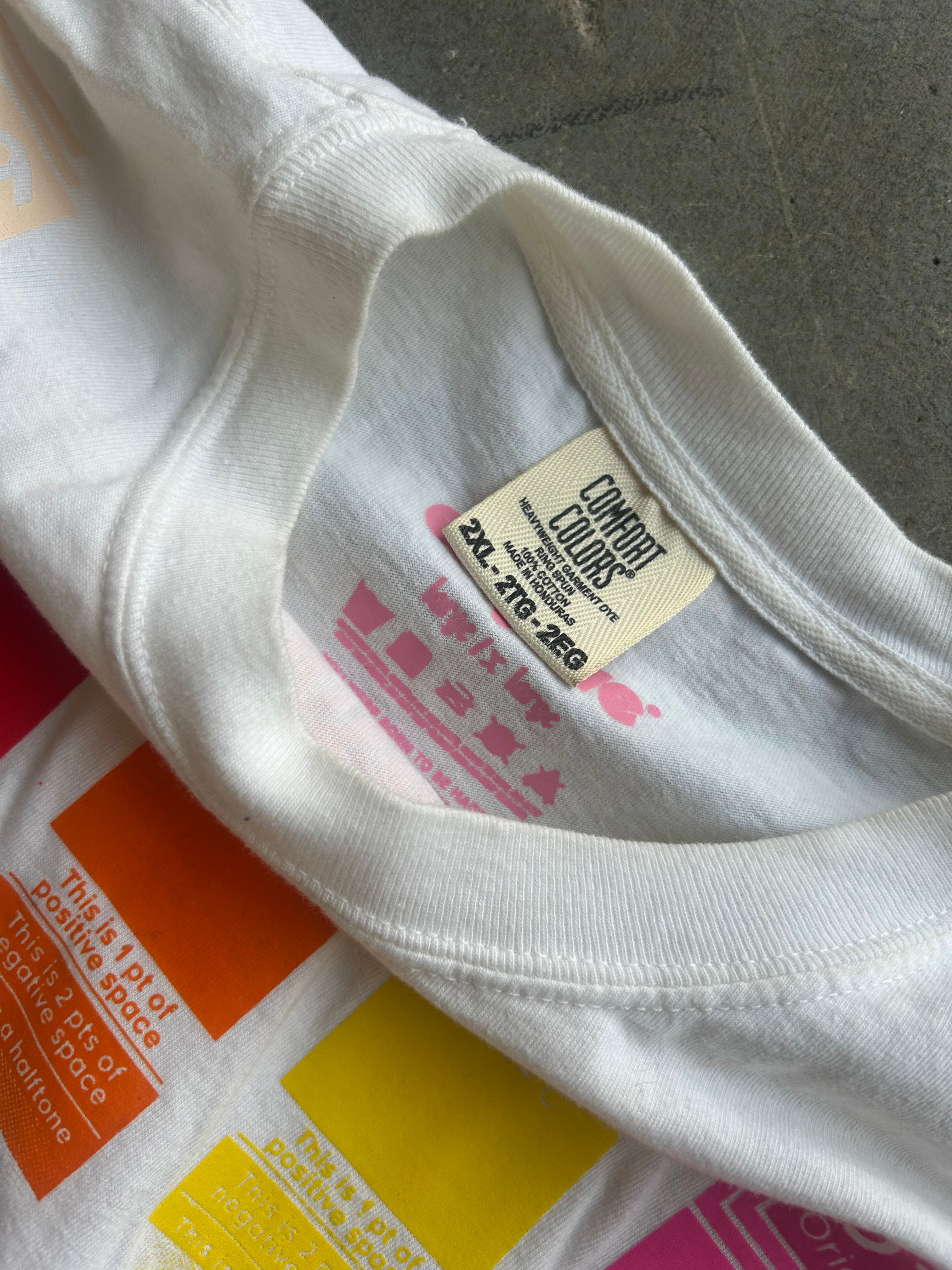 Close-up of a white crewneck t-shirt showing the inner neck label which reads 'COMFORT COLORS' and '2XL - 210-220'