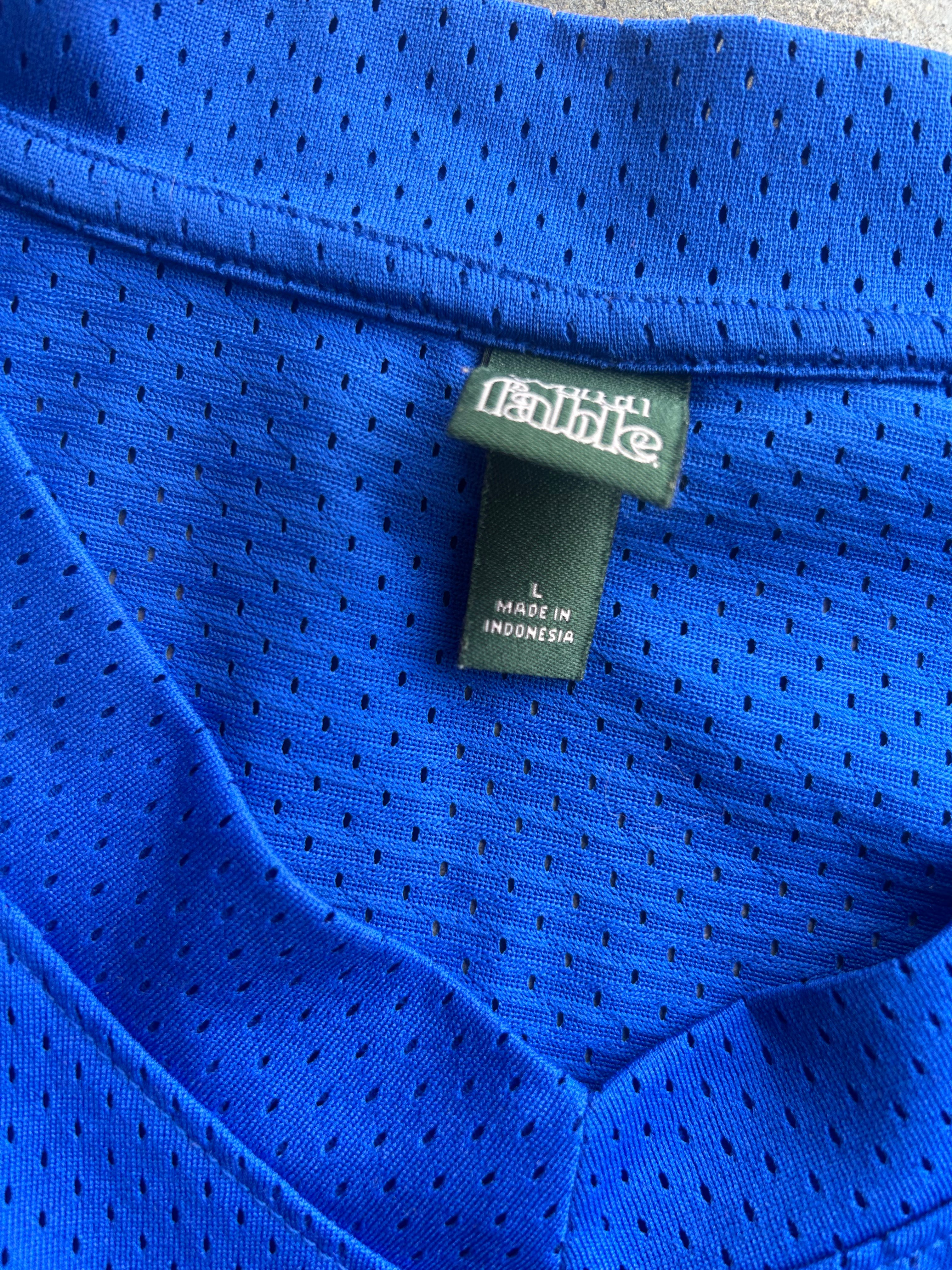 Close-up of a bright blue mesh athletic shirt showing the inner neck label with 'Fab' branding and 'MADE IN INDONESIA' text