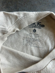 Close-up of the inside collar of a light beige cotton t-shirt, showing the printed brand label 'PINK FOOD CLOTHING' and size information