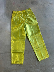 Metallic lime green cropped pants with a shiny, crinkled texture, laid flat on a gray concrete floor