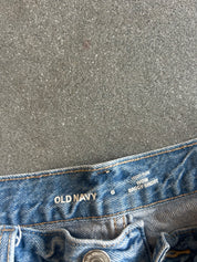 Close-up of the waistband of light blue denim jeans on a textured gray background, showing the Old Navy brand name