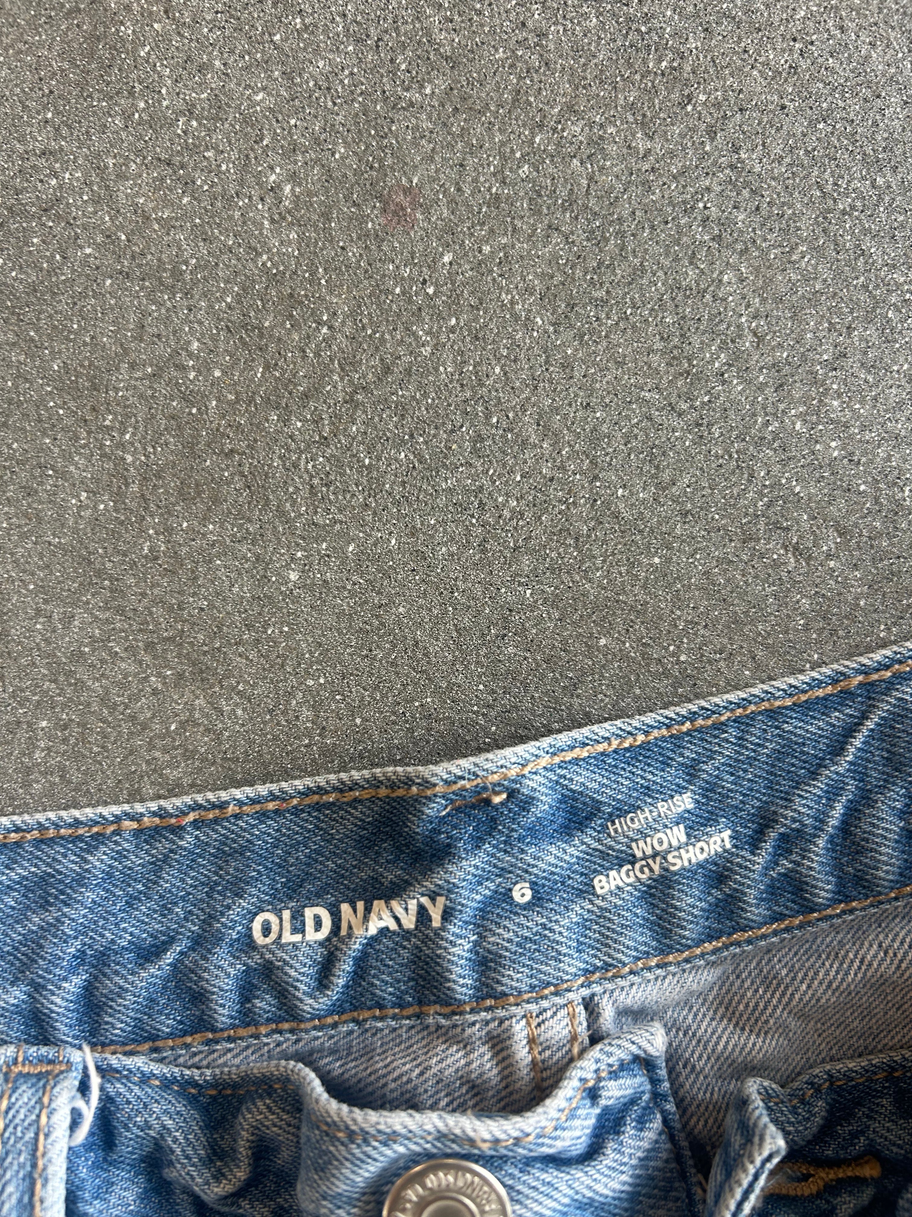 Close-up of the waistband of light blue denim jeans on a textured gray background, showing the Old Navy brand name