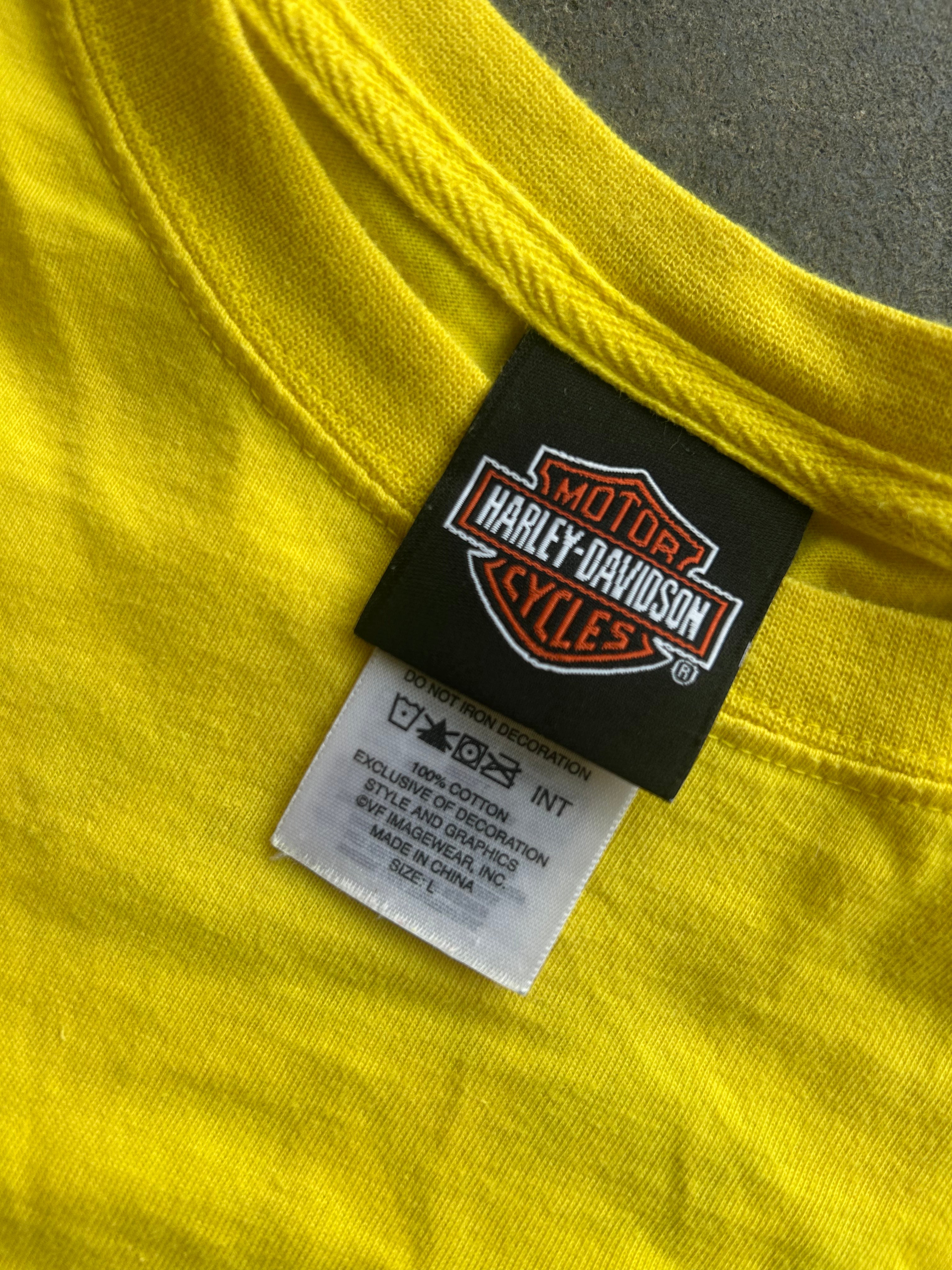Close-up of a bright yellow t-shirt showing the inner neck label with a black Harley-Davidson patch and a white care tag