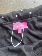 Close-up of a black garment with a pink tag reading 'colortone' and a white cord loop, laid on a gray concrete surface