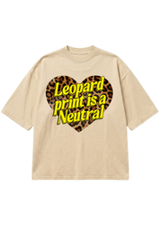 A beige short-sleeve t-shirt with a graphic on the chest featuring a leopard print heart and the text 'Leopard print is a Neutral' in yellow with black outlines
