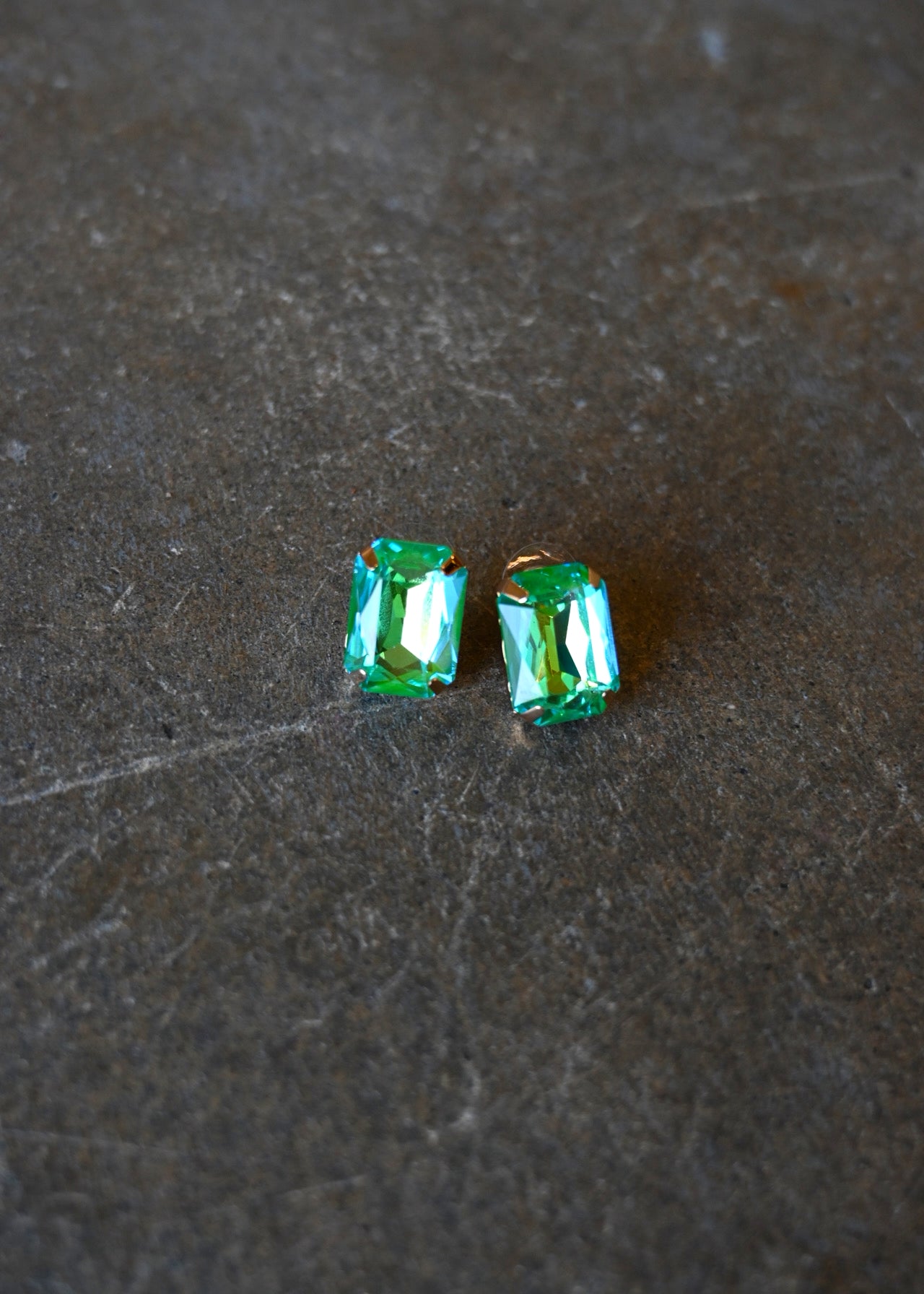 Emerald cut teal earrings on a dark background