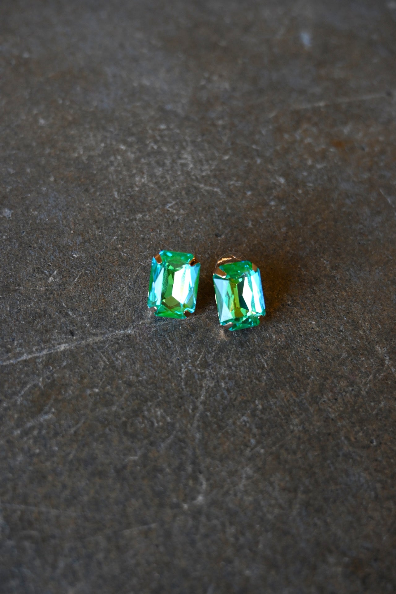 Emerald cut teal earrings on a dark background