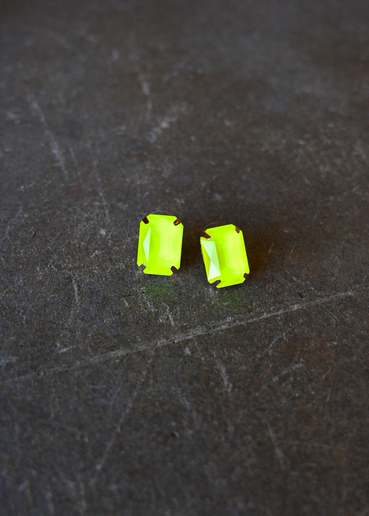 Emerald cut neon yellow earrings on a dark background