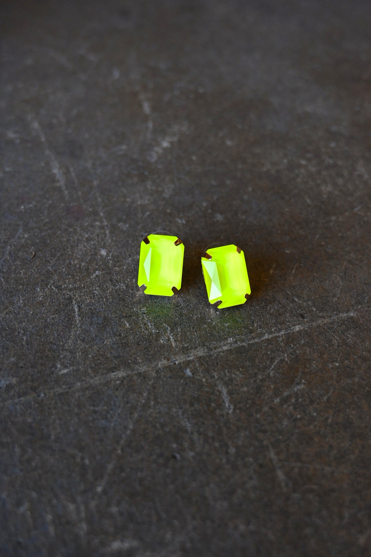Emerald cut neon yellow earrings on a dark background